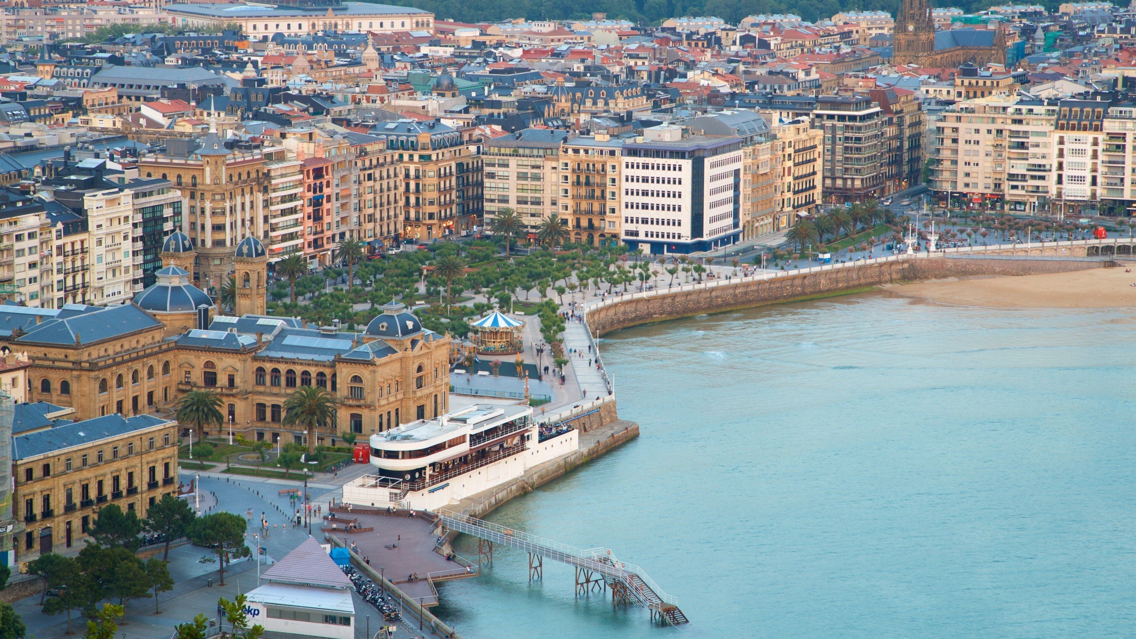 A coastal cityscape with historic buildings, a promenade, and a waterfront promenade.