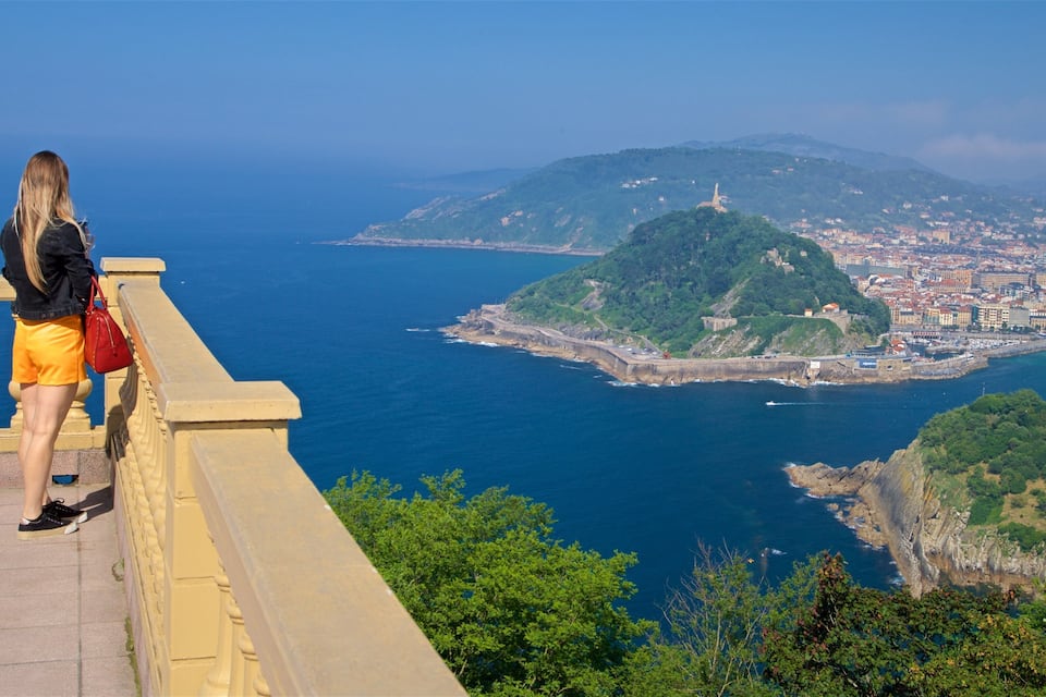 A coastal cityscape with a prominent hill and a lighthouse.