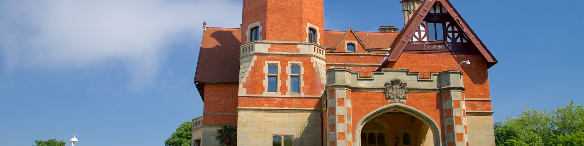 Um grande edifício de tijolos com torre e entrada em arco.