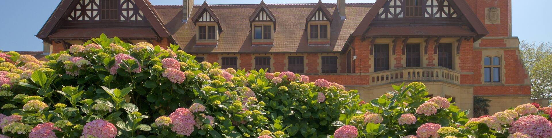 A large, historic building with Tudor-style architecture, including steeply pitched gable roofs and decorative half-timbering.
