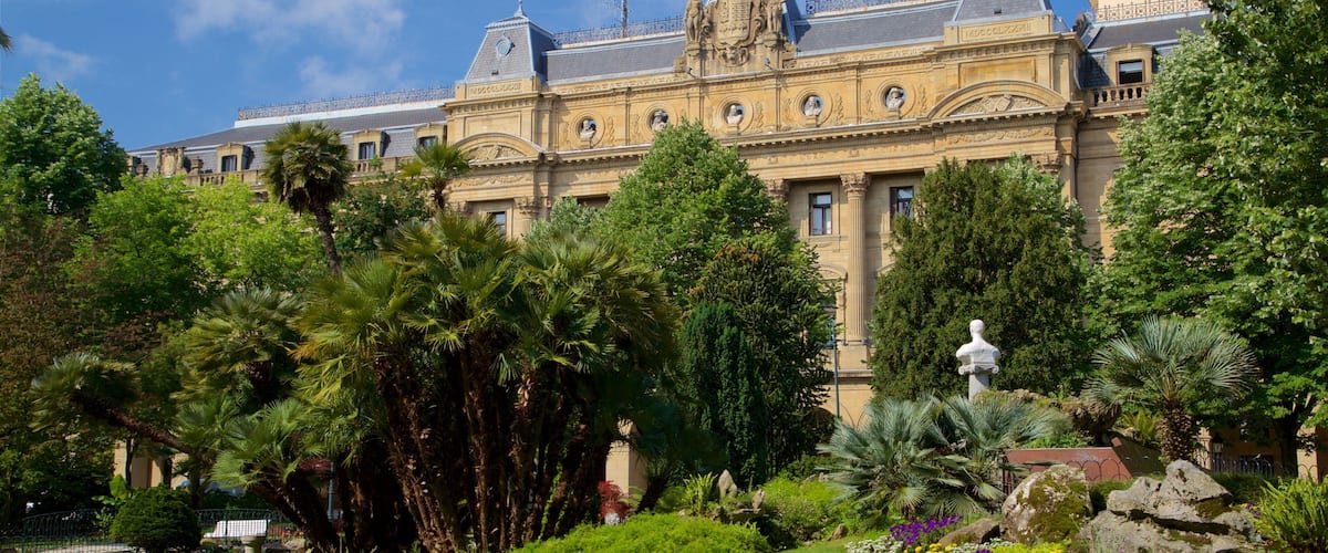 A grand building with ornate architecture, lush greenery, and a well-maintained garden.