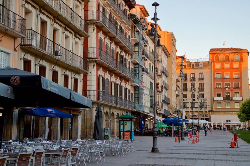 A street lined with cafes and outdoor seating, with buildings featuring balconies and ornate architectural details.
