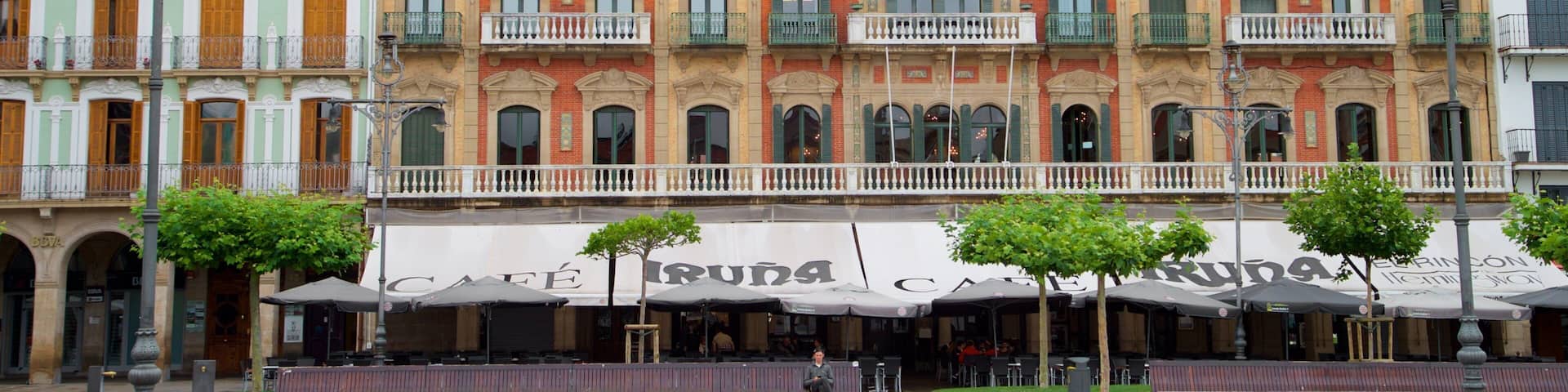 A row of colorful buildings with balconies and a cafe named "Café Irunda" in front.