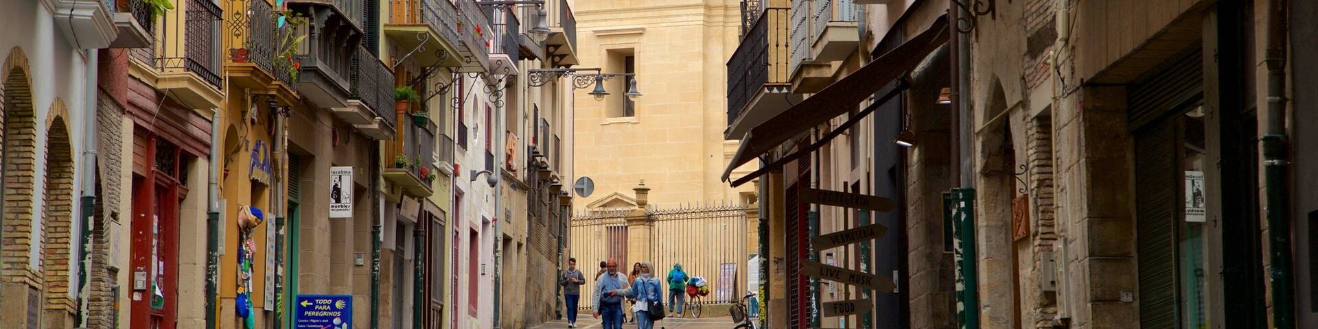 A narrow street with colorful buildings, a clock tower, and people walking.