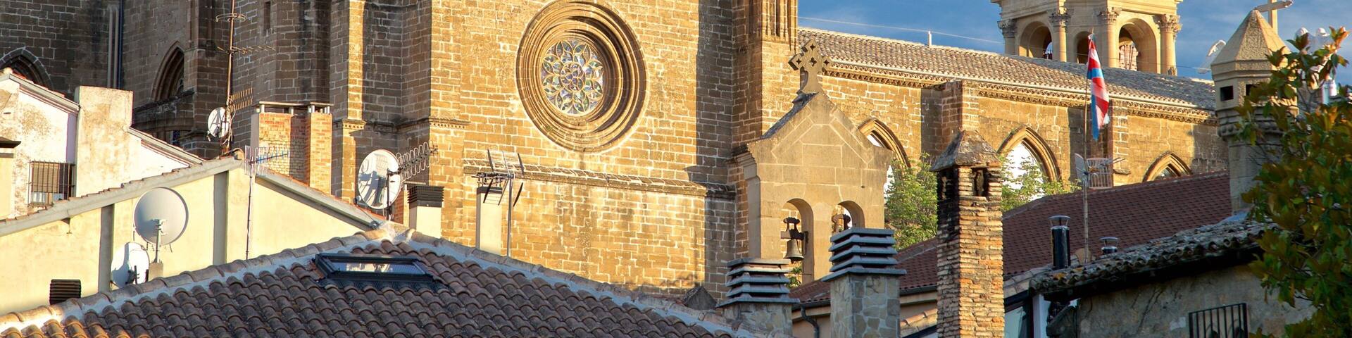 A historic church with a large circular window, a bell tower, and a cross on top.