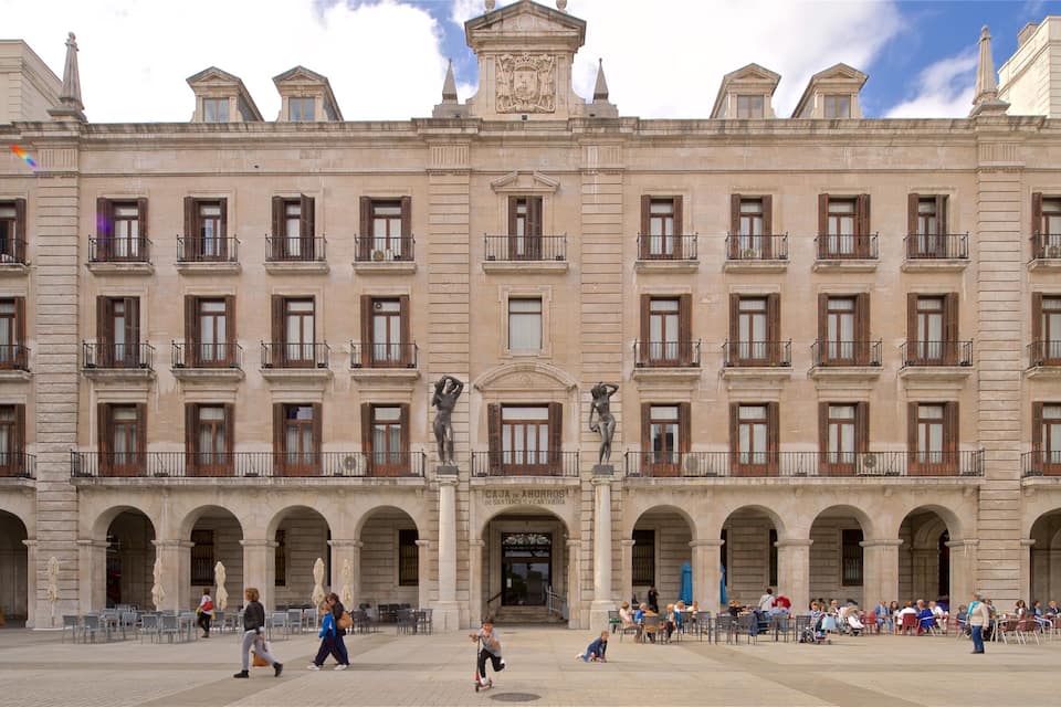 A historic building with multiple balconies and statues in front.