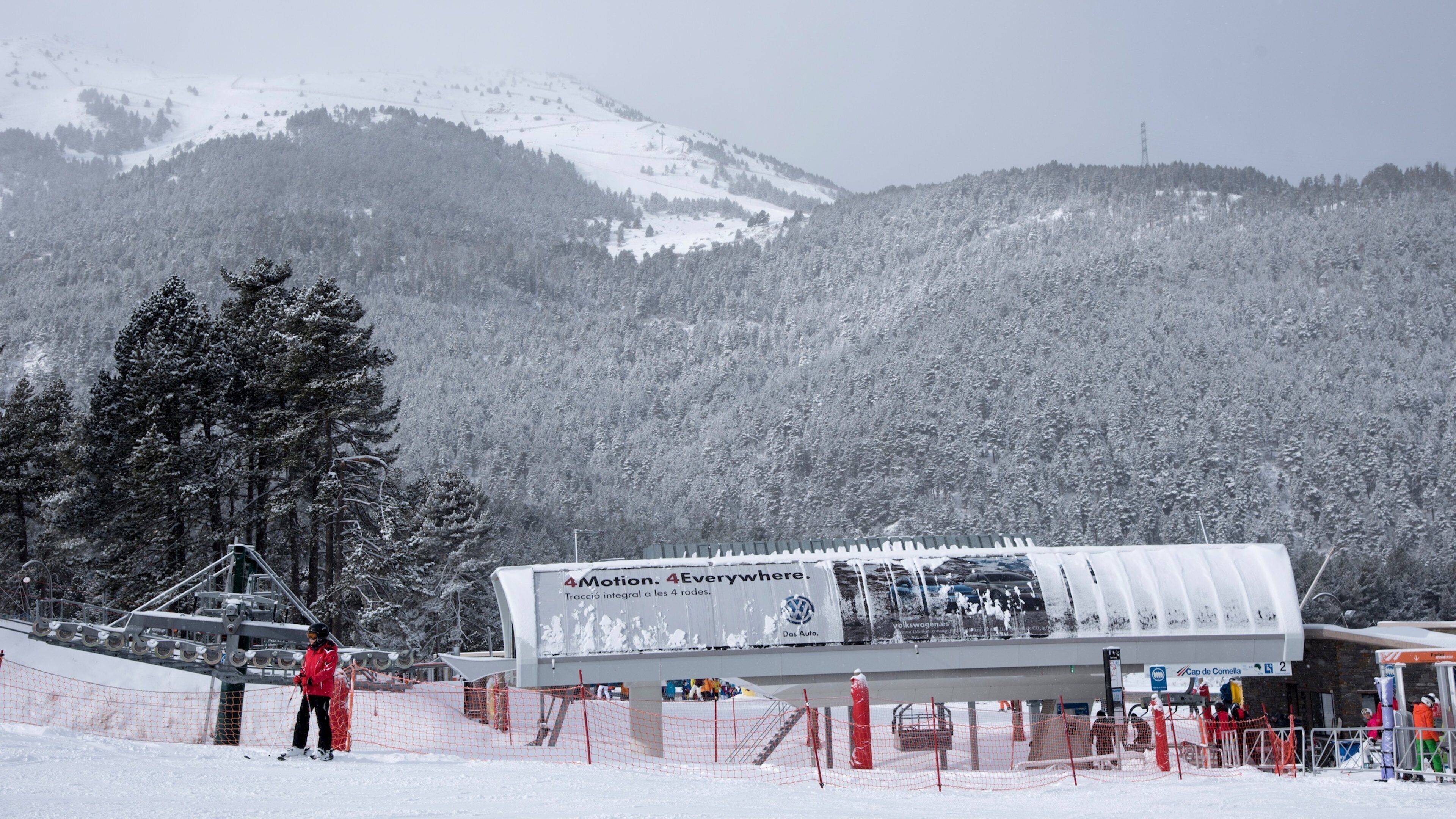 A ski lift station with a snow-covered mountain backdrop.