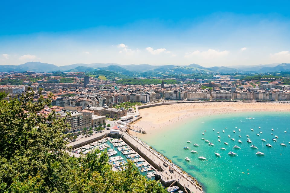 A coastal city with a bay, marina, and mountainous background.