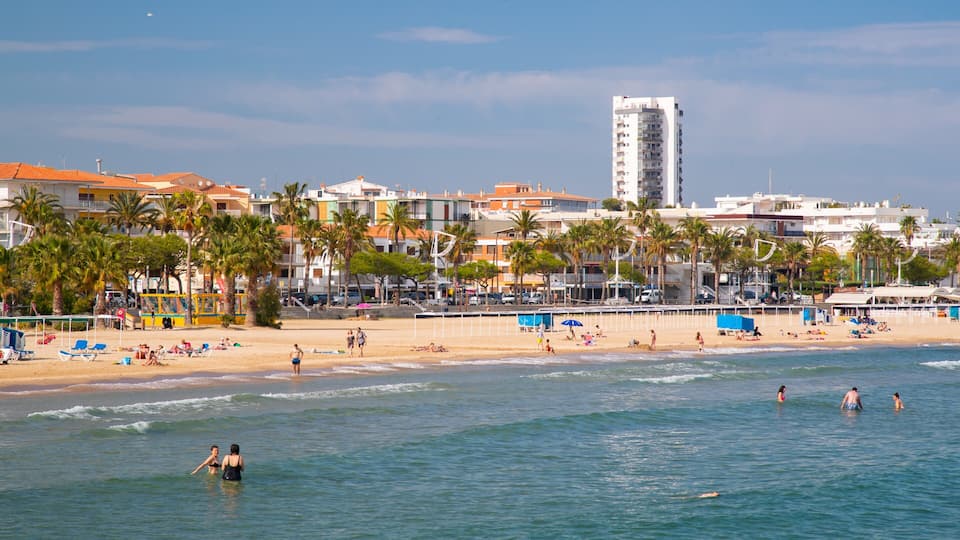 A beach with palm trees, people swimming, and buildings in the background.