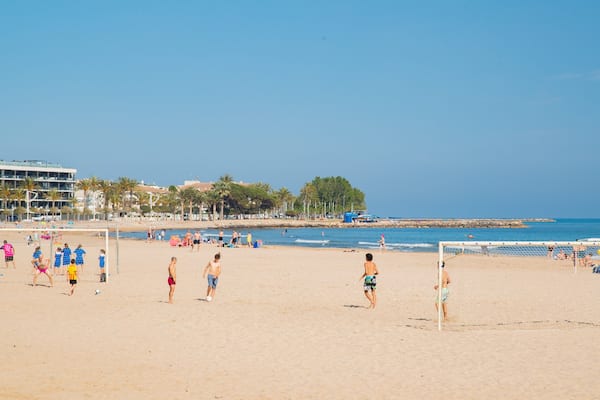 Jogo de voleibol de praia com jogadores e espectadores.