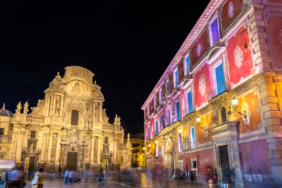 Una catedral histórica con arquitectura intrincada y un edificio vibrante con iluminación de colores.