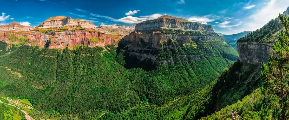 A mountainous landscape with prominent cliffs and dense forest.