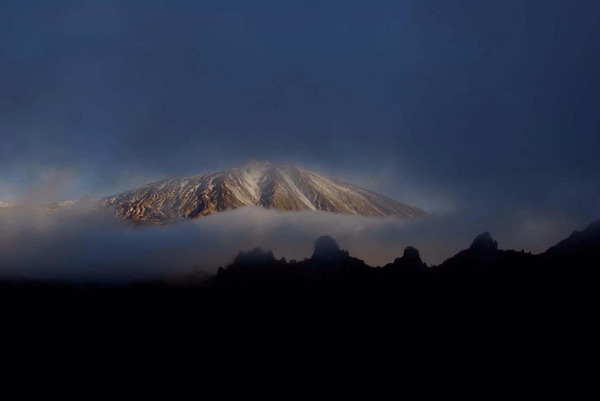 A snow-capped mountain partially obscured by clouds.