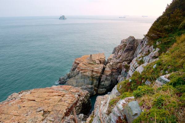 Une falaise côtière avec un rivage rocheux et une mer calme.