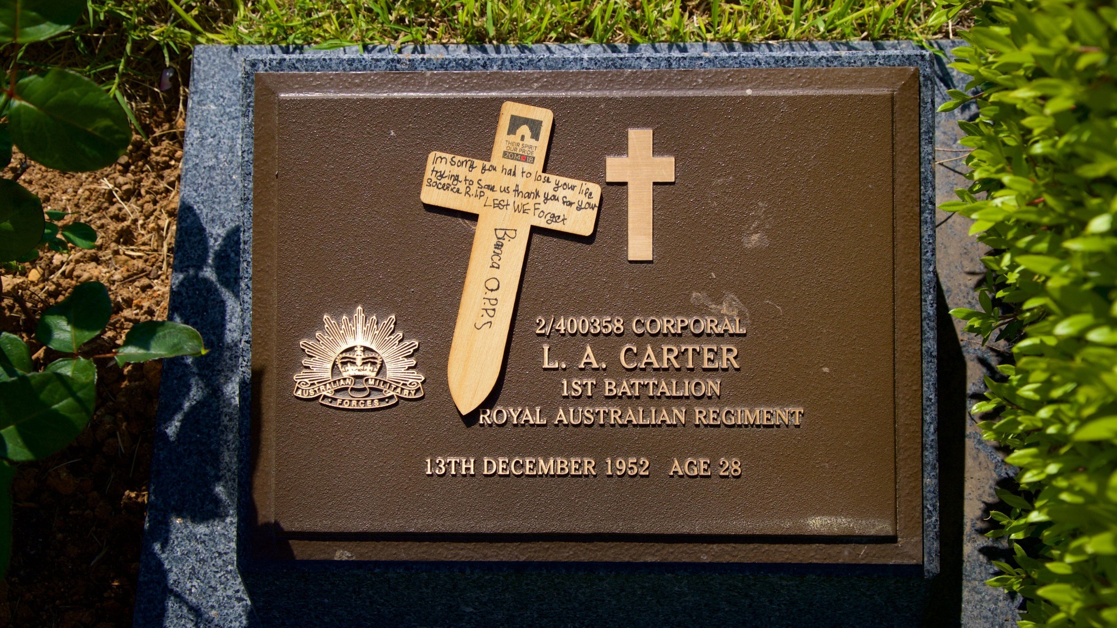 Una placa conmemorativa con una cruz, inscripciones y el emblema militar australiano.