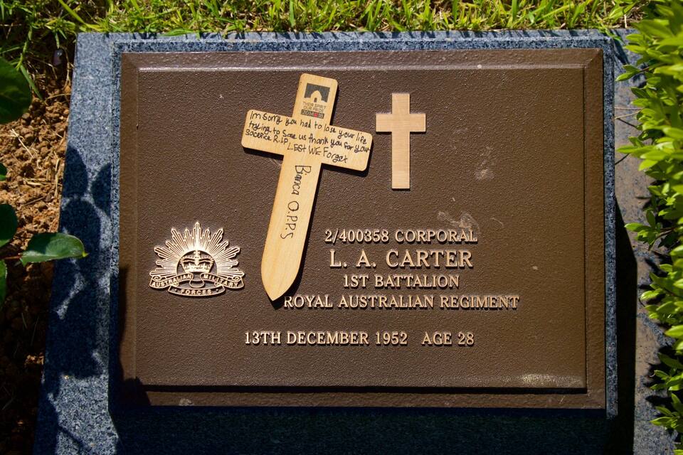 Una placa conmemorativa con una cruz, inscripciones y el emblema militar australiano.