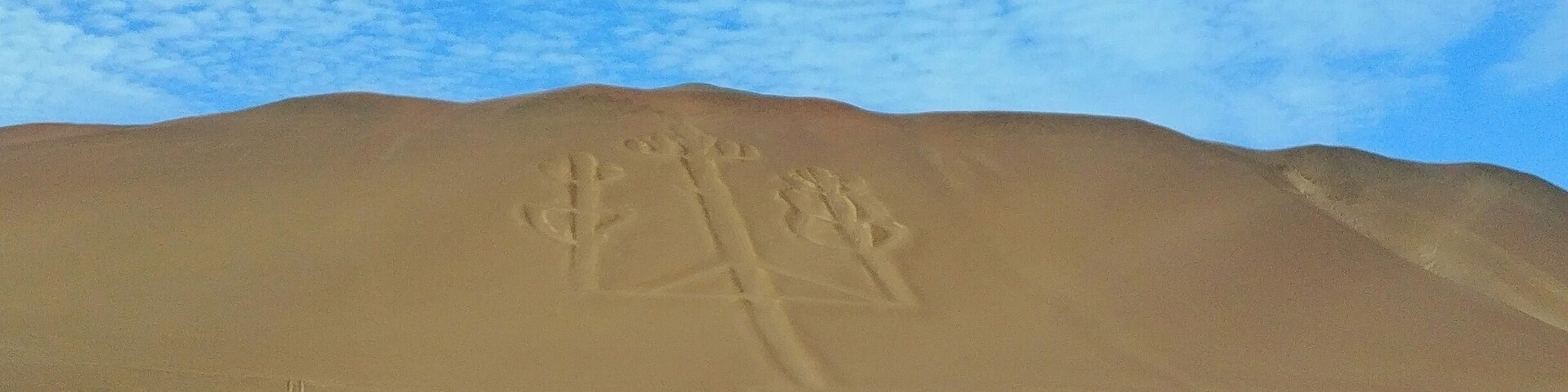 Paisaje desértico con una duna de arena grande y una formación rocosa en primer plano.