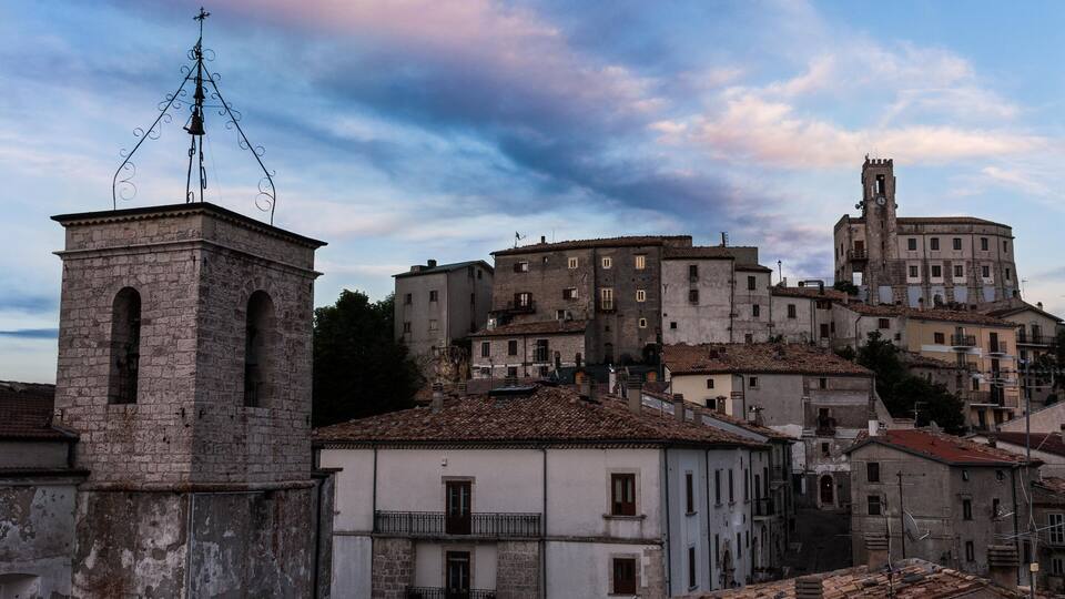 A historic town with stone buildings, a bell tower, and a church with a clock tower.