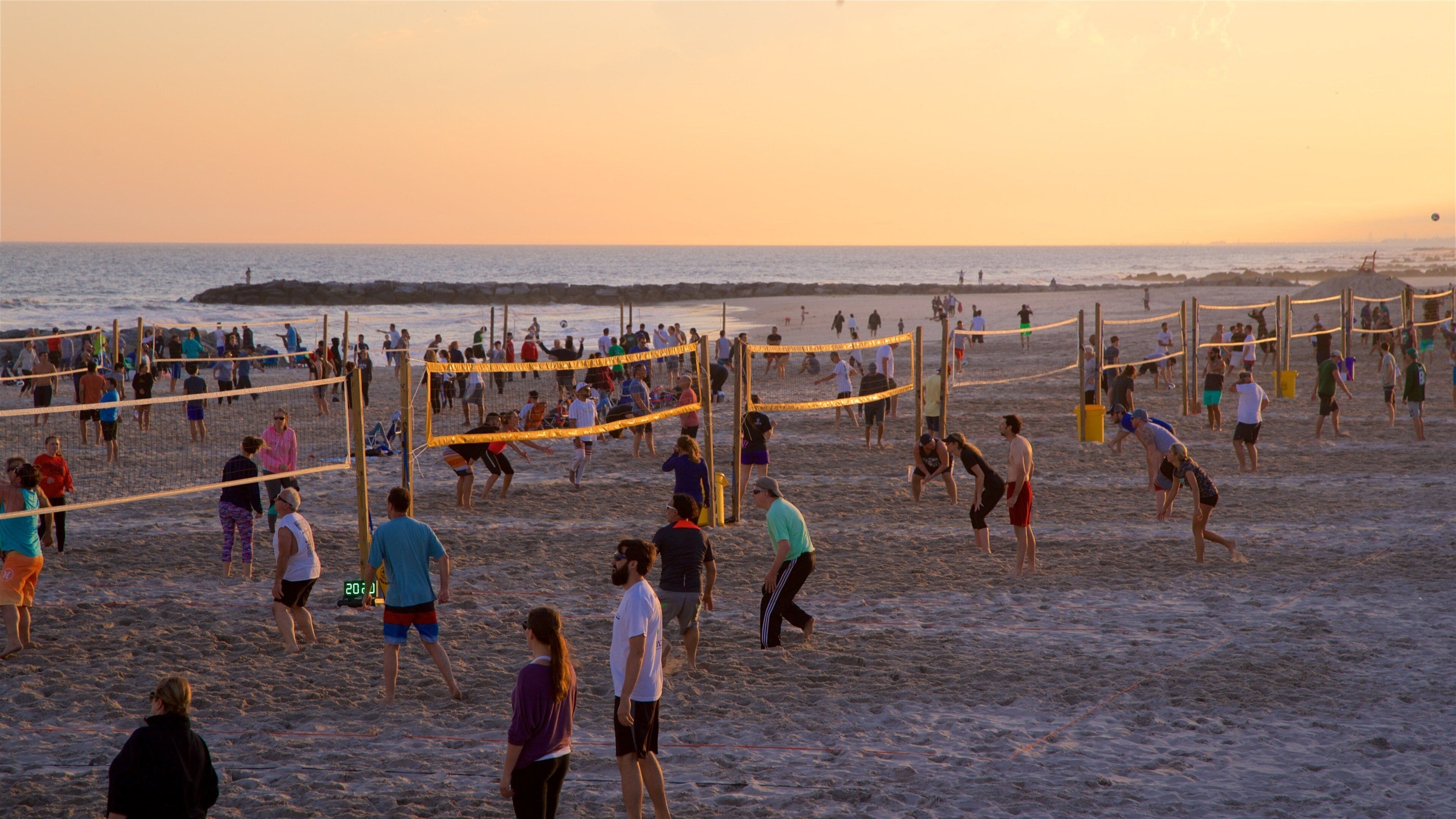 A beach volleyball game with a net and players in the sand.