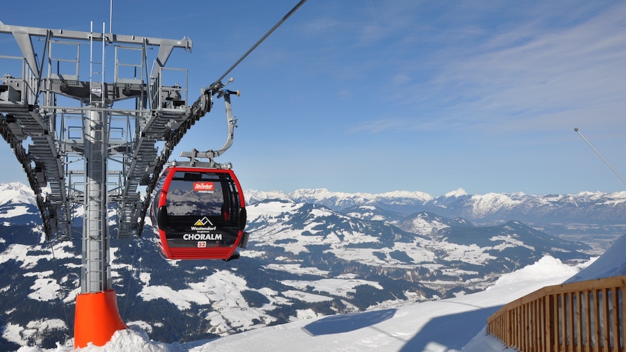 A ski lift chair ascending a snowy mountain with a clear sky.