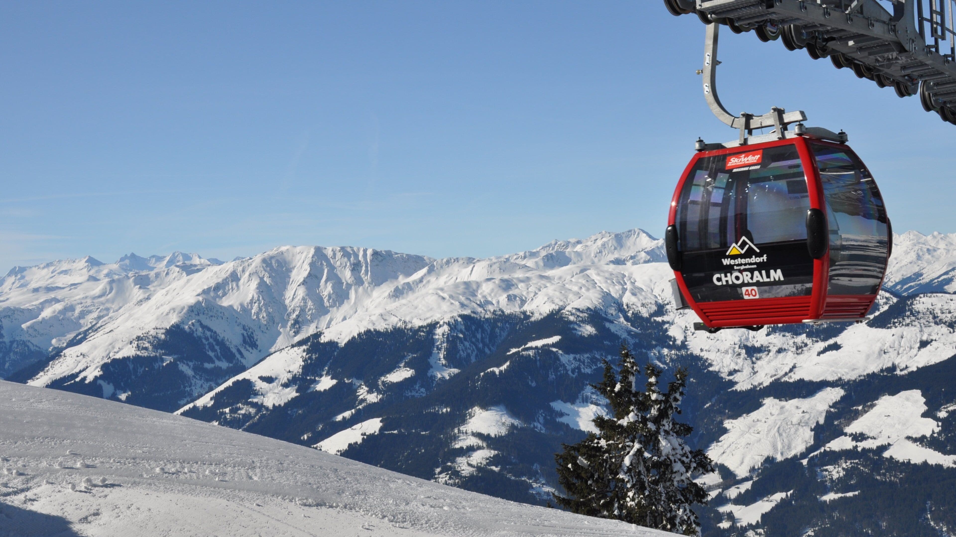 A red cable car labeled "Choraim" at Westendort, with snow-covered mountains in the background.