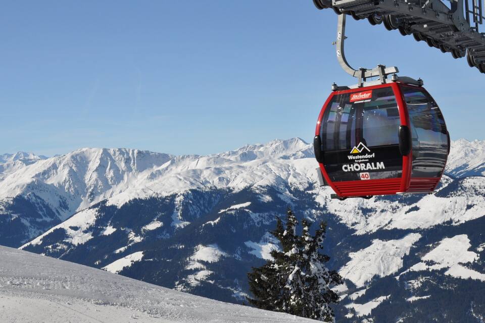 A red cable car labeled "Choraim" at Westendort, with snow-covered mountains in the background.