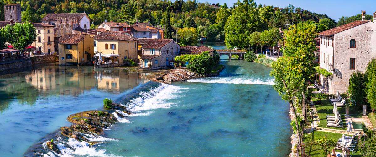A river flowing through a town with historic buildings and a bridge.