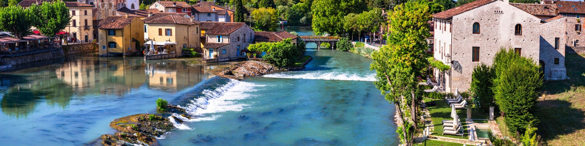 A river flowing through a town with historic buildings and a bridge.