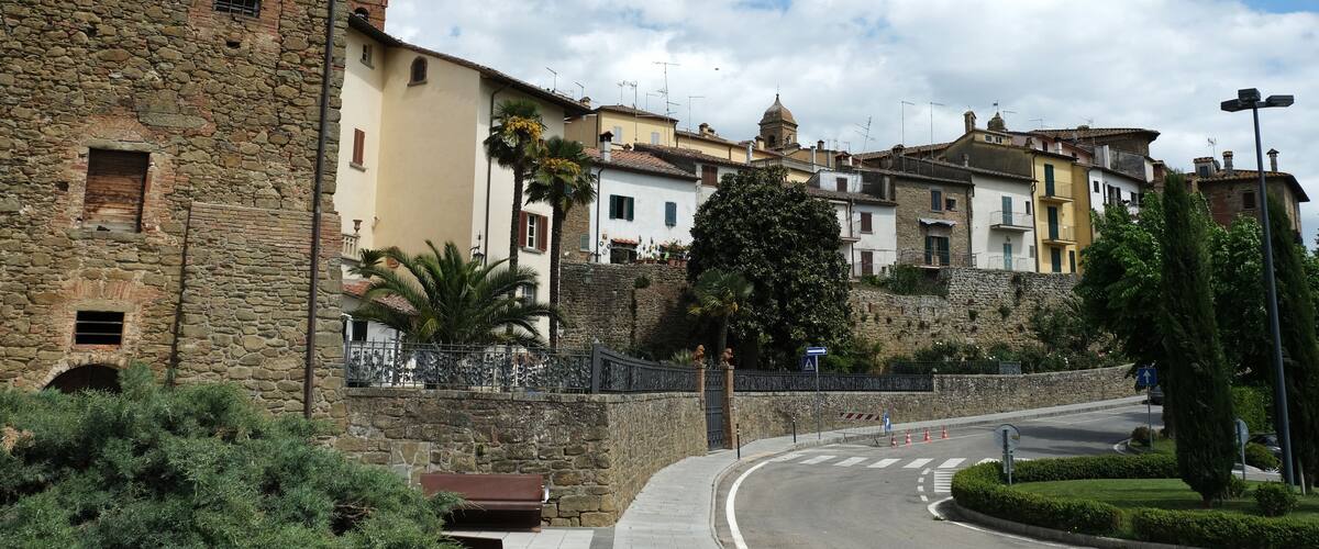 A stone tower, a curved road, and traditional buildings with a stone wall.