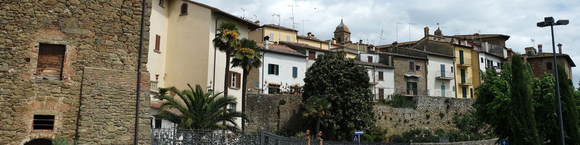 A stone tower, a curved road, and traditional buildings with a stone wall.