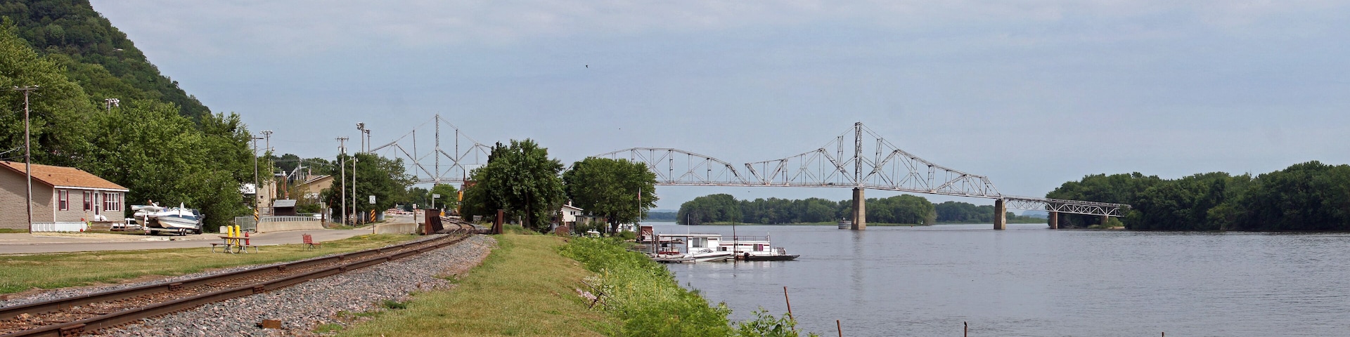 A river with a bridge, a dock, and a train track.