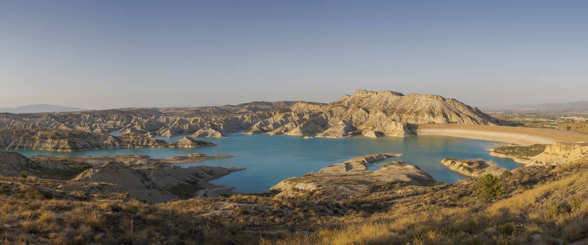 A rugged landscape with a large body of water surrounded by rocky terrain and sparse vegetation.