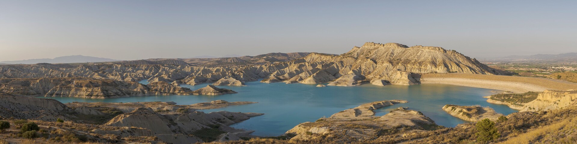 A rugged landscape with a large body of water surrounded by rocky terrain and sparse vegetation.