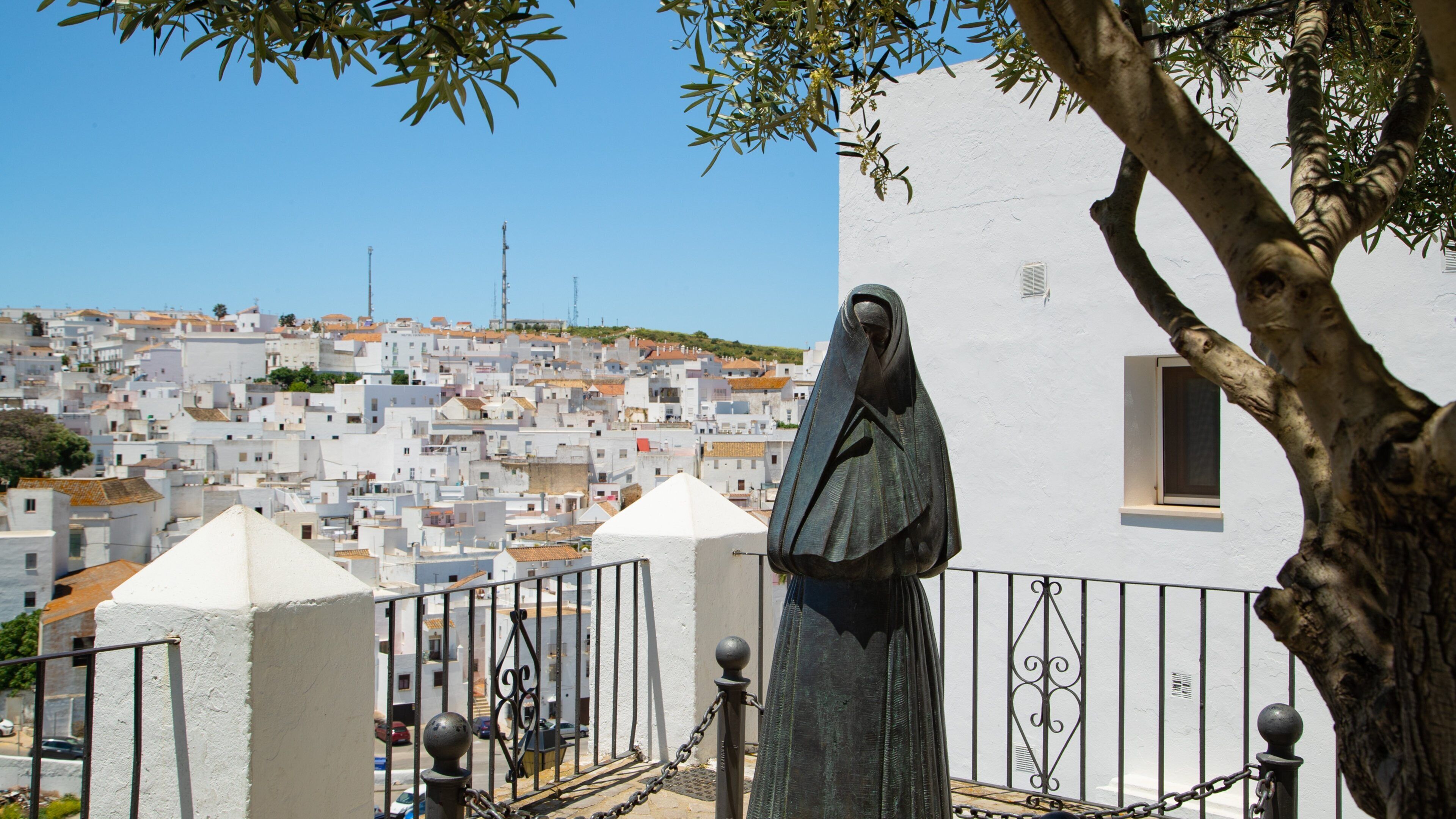 A statue of a woman in a white building with a view of a densely packed town in the background.