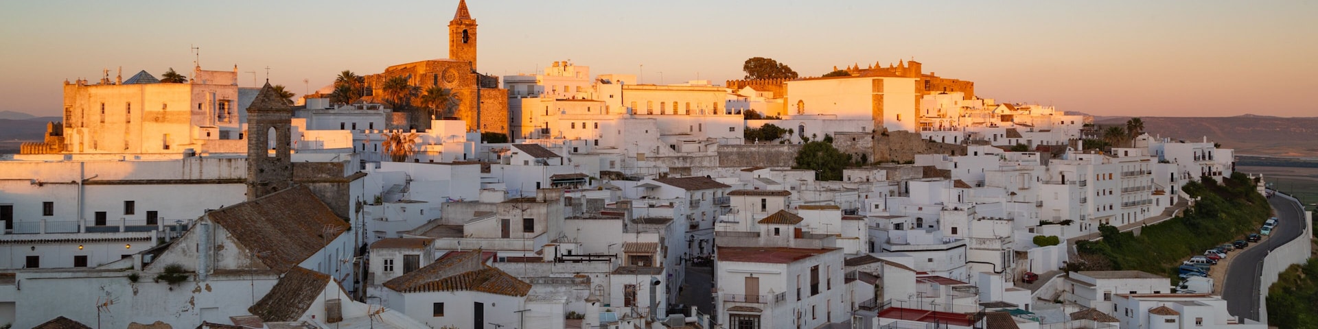Un pueblo costero con edificios blancos, una iglesia destacada y un castillo fortificado.