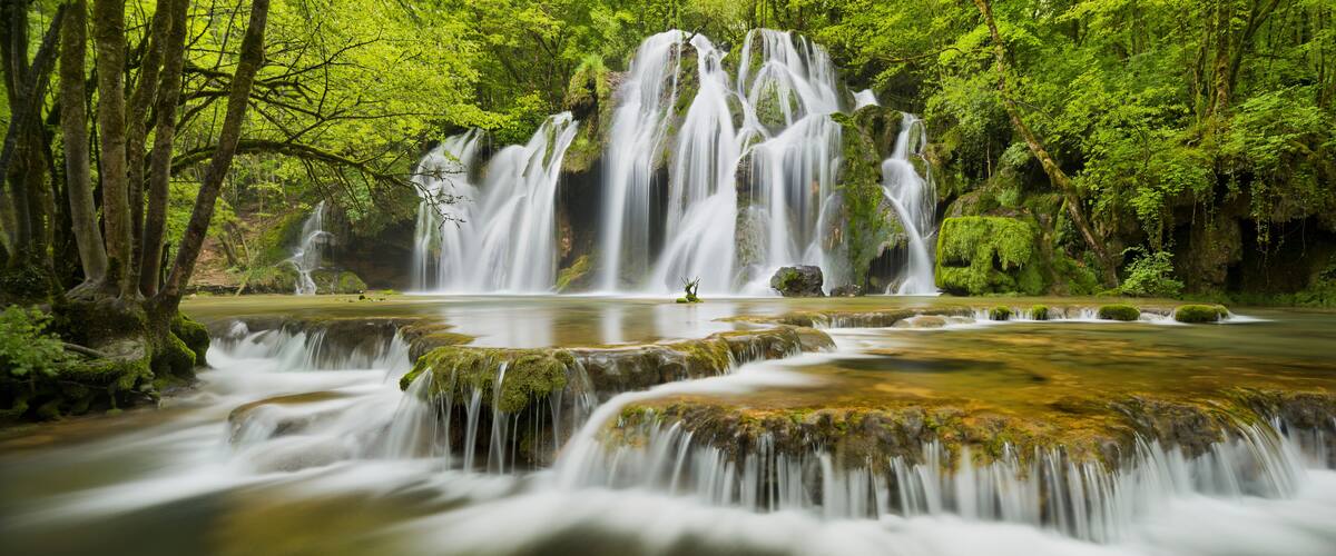 A waterfall cascading over moss-covered rocks in a lush forest.