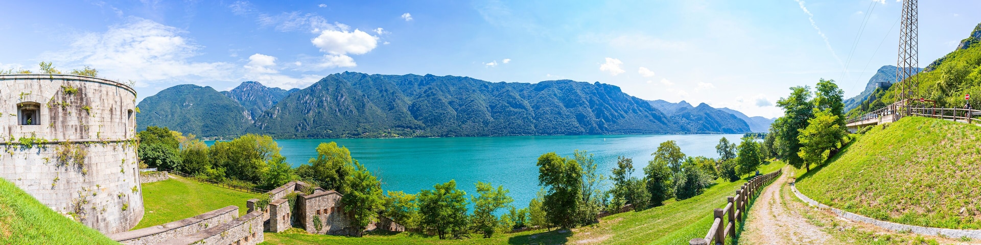 Una torre de piedra histórica, un lago y un paisaje montañoso.