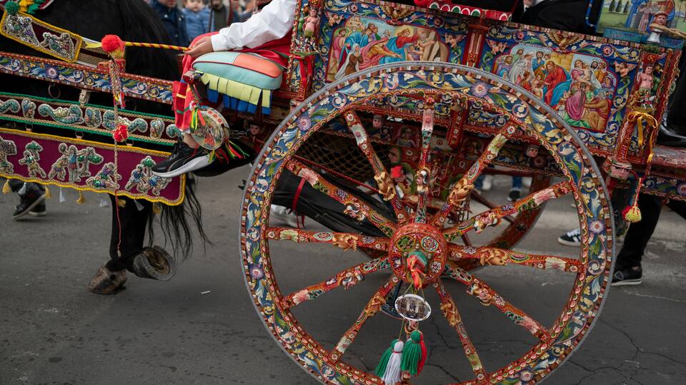 A decorated horse-drawn carriage with intricate artwork and tassels.