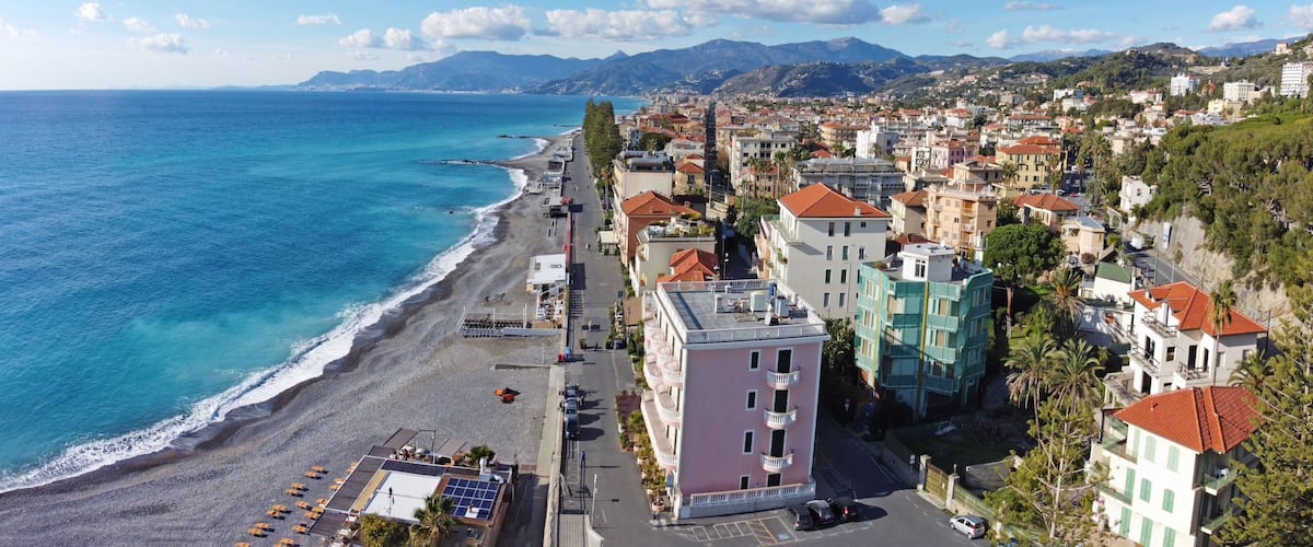 A coastal town with a beach, buildings, and mountains in the background.