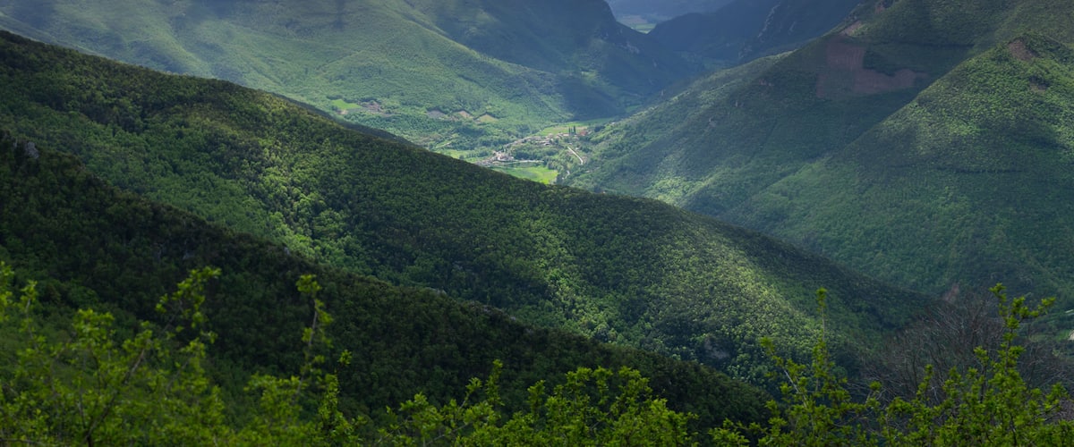 A valley with lush green hills and a small village nestled in the valley.