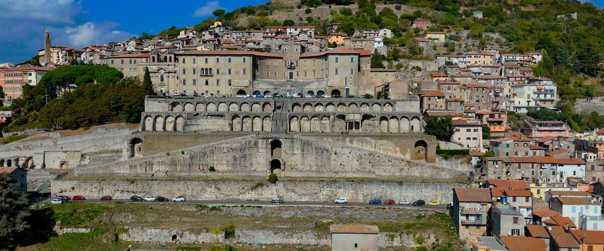 A historic city with a prominent ancient amphitheater and a hilltop church.