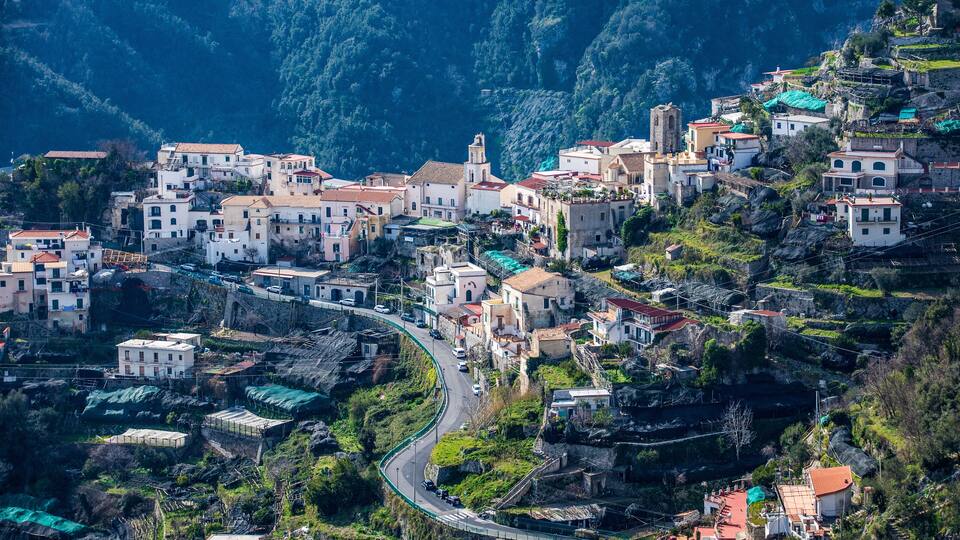 A hillside village with terraced houses, a winding road, and a prominent church.