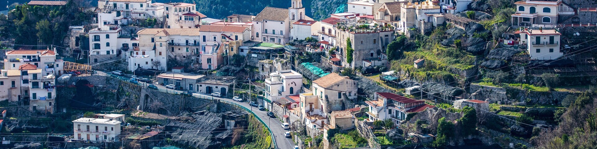 Un pueblo en la ladera con casas escalonadas, un camino sinuoso y una iglesia destacada.