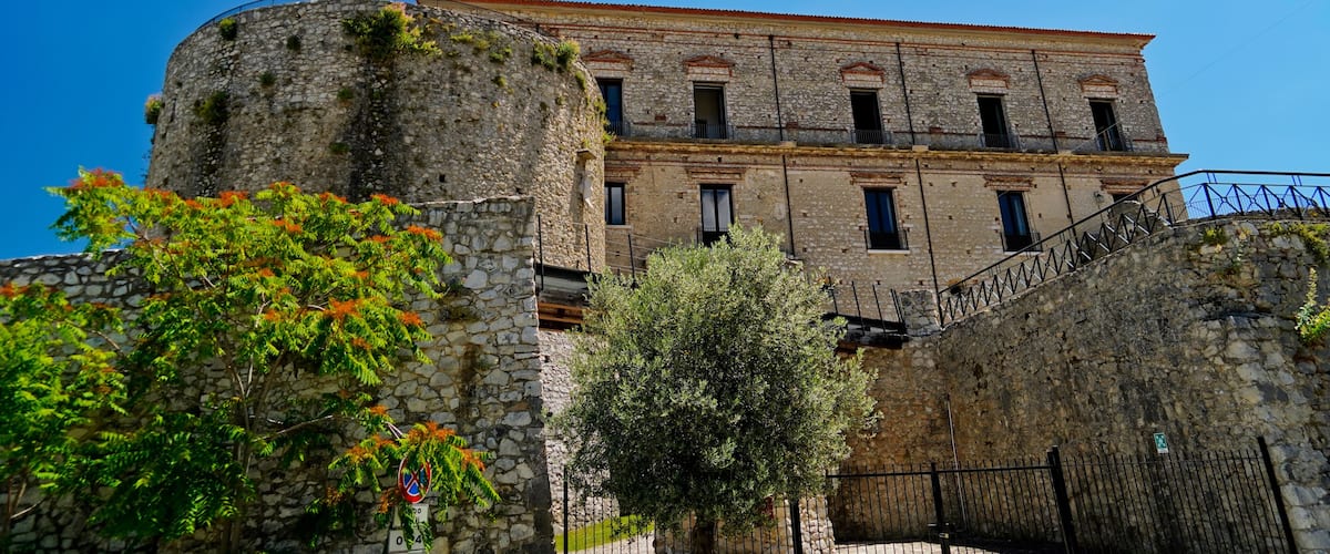 A historic stone building with a red-tiled roof and a stone tower.