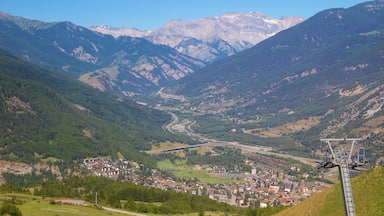 Paisagem montanhosa com vale, estrada sinuosa e teleférico.