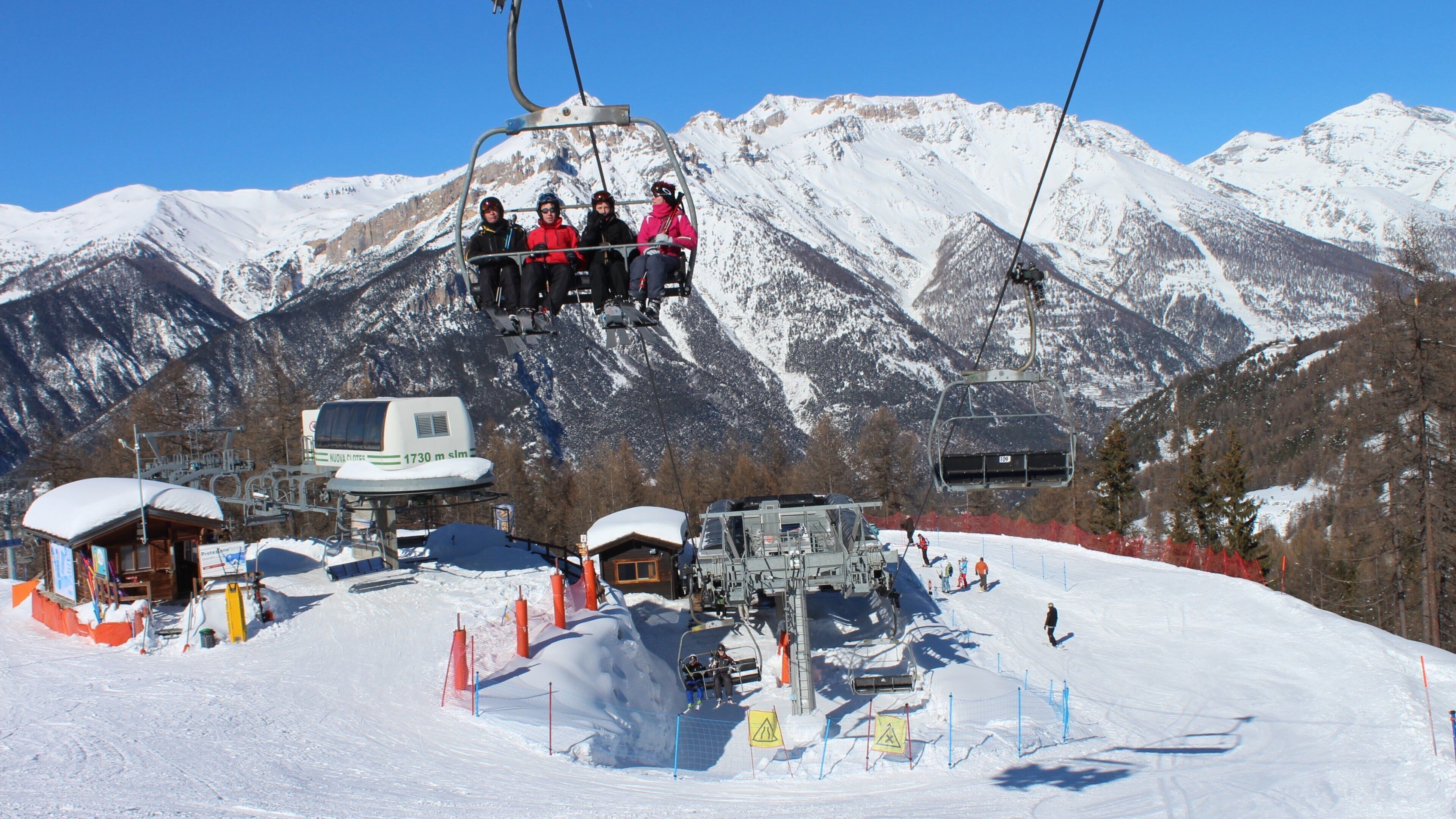 A ski lift with skiers and a mountain backdrop.