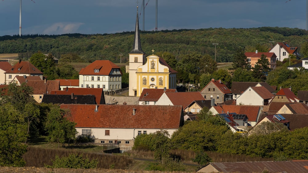 Un village rural doté d’éoliennes, d’une église et de maisons d’habitation.