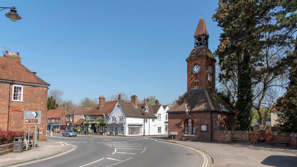 A street with a church tower, a pub, and a signpost.