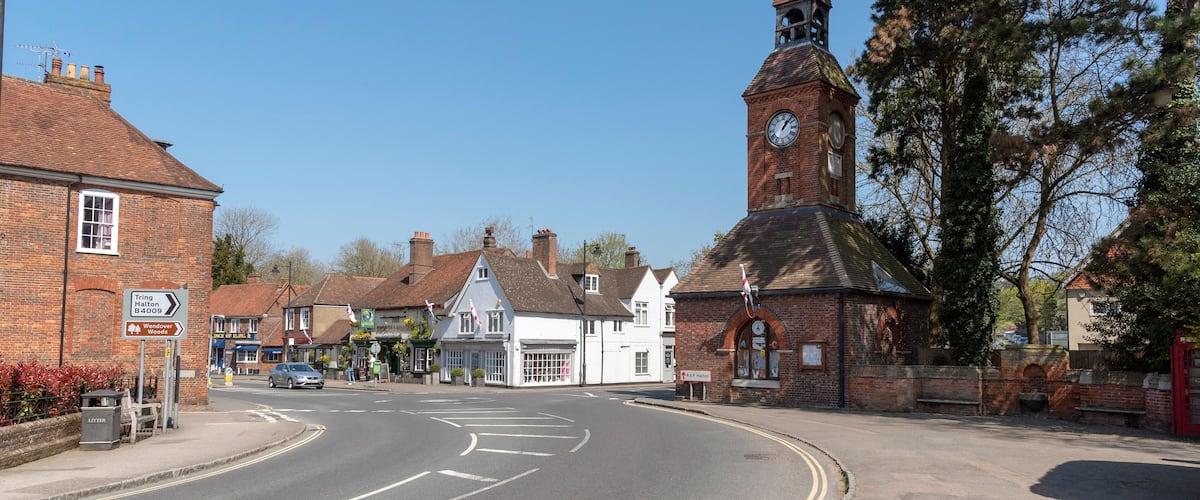 A street with a church tower, a pub, and a signpost.