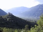 Un castello su una collina che domina una valle con montagne sullo sfondo.